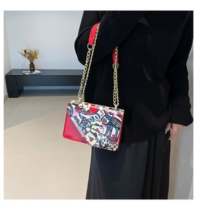 Close-up of red graffiti crossbody bag with gold chain strap and chic street style motifs