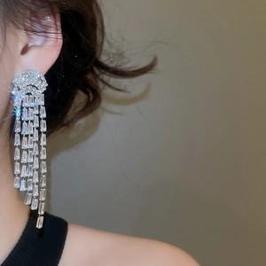 Détail de boucles d'oreilles longues à pampilles serties de zircons en finition argentée
