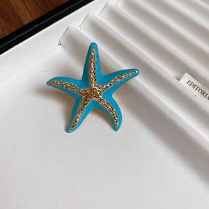 Macro shot of blue starfish open ring with gold trim on a white display tray