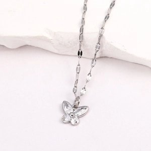 Vue macro du pendentif papillon argenté serti de zircons sur un support en pierre blanche
