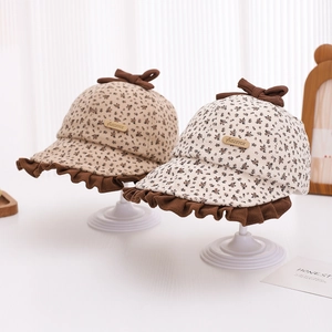 Detail of baby floral bucket hats with ruffles and a brown bow on a white stand