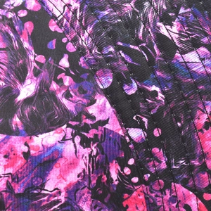 Macro detail of quilted tie-dye fabric with purple and pink abstract graffiti pattern