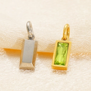 Macro shot of silver and gold rectangular birthstone pendants on soft beige silk