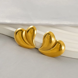 Boucles d'oreilles cœur en acier inoxydable doré 18K sur un socle blanc ondulé