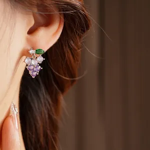 Grape cluster drop earrings with purple zircon crystals worn by a model in soft light