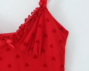 Détail du tissu en maille rouge avec motifs cœurs gaufrés et bordure à volants