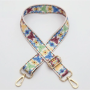Detail of woven bag strap with colorful butterfly embroidery and gold metal hardware