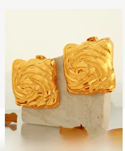 Makroaufnahme goldener quadratischer Ohrstecker mit Rosenmuster auf Steinunterlage