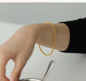 Close-up of a delicate gold-toned rope chain bracelet worn on a woman's wrist