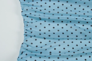 Détail du tissu en maille bleu clair à pois noirs avec texture froncée latérale