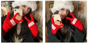Detail of red knit gloves with white fabric patch and French embroidery on the back