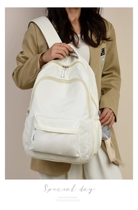 Detail of white nylon backpack with front zipper pocket and multi-compartment storage