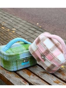 Detalle de neceseres de peluche a cuadros con cremalleras metálicas de corazón