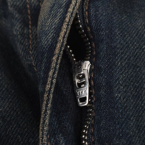 Primer plano de la cremallera metálica YKK de alta calidad en unos vaqueros azul oscuro
