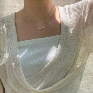 Close-up of a minimalist silver teardrop pendant necklace worn with elegant casual attire