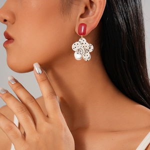 Close-up of model wearing floral stud earring with red square and polka dot petals