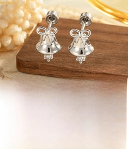 Detail of silver bow bell cartilage stud earring with cubic zirconia on a wooden stand