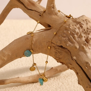 Detail of 18K gold-plated anklet with shell charms and amazonite stones on wood