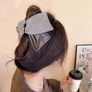 Detail of elegant two-tone fabric and leather bow hair clip on model back hairstyle