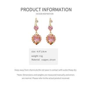 Detail of pink heart zircon drop earrings with golden copper hooks and side crystals