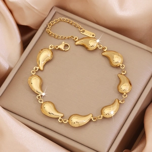 Detail of a gold waterdrop-shaped link bracelet with lobster clasp on satin fabric