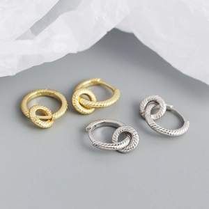 Detail of twisted rope interlocking earrings in gold and silver finish on soft paper