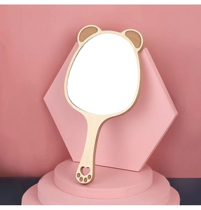 Close-up of a bear-shaped wooden hand mirror on a pink pedestal with paw-cutout handle