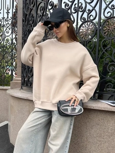 Detail of beige oversized crewneck sweatshirt featuring ribbed cuffs and dropped shoulders
