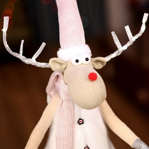 Close-up of a pink knitted Christmas reindeer plush with silver antlers and soft textures