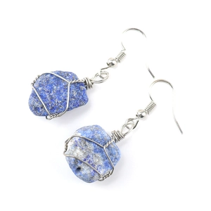 Macro detail of handmade silver wire wrapped raw blue lapis lazuli stone earrings