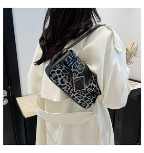 Detail of leopard print shoulder bag with gold geometric clasp on a white coat