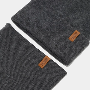 Detailed close-up of dark grey knitted beanie and neck warmer with leather patch