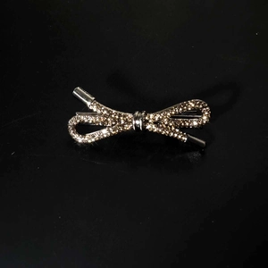 Detailed view of elegant silver bow hair clip with sparkling rhinestones on black background