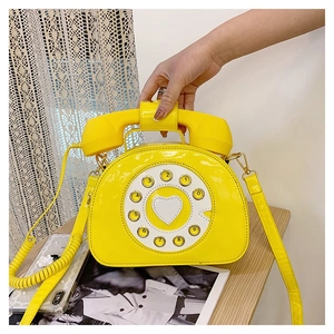 Detail of yellow patent leather crossbody bag featuring a vintage telephone dial design