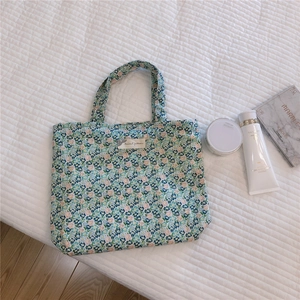 Détail du sac cabas en toile fleurie avec motifs bleus et roses et poignées