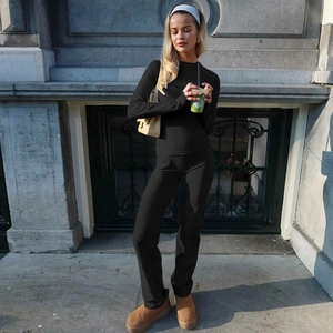 Detail of a women's black long sleeve top and high waist trousers in an outdoor street setting