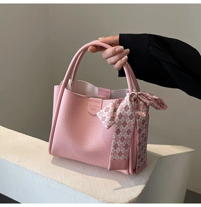 Detailed shot of pink lychee leather bucket bag with a checkered silk scarf accessory