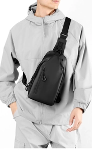 Detailed view of a sleek black crossbody chest bag with adjustable strap on a male model