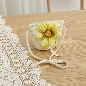 Détail d'un sac à bandoulière en paille avec une grande décoration de tournesol sur table