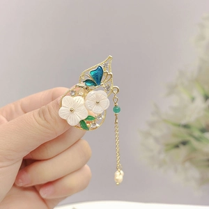 Detail of vintage gold pipa brooch with butterfly, white flowers and pearl tassels