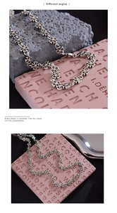 Detail of vintage silver cross necklace with metal beaded chain against stone background