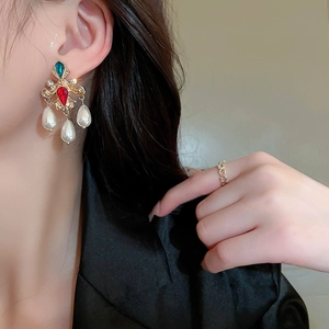 Vintage gold earrings with colorful crystals and hanging pearls worn by a model