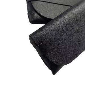 Minimalist black pebbled leather glasses case with soft texture and folding flap closure