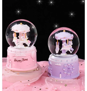 Pink and purple carousel crystal balls with unicorn figurines on dreamy tulle background