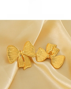 Détail de boucles d'oreilles nœud dorées avec finition en métal brossé et tige arrière