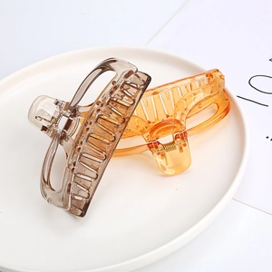 Macro view of translucent amber and charcoal resin hair claws in a white tray