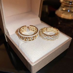 Macro detail of gold open rings with pearls and zircon in a beige jewelry box
