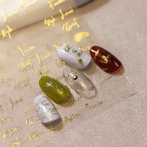 Macro shot of gold relief butterfly nail stickers with cursive typography on tips