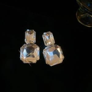 Macro detail of silver square crystal earrings featuring a stacked geometric drop design