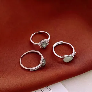 Silver open ring set with green cabochon stones and zircon accents on brown silk